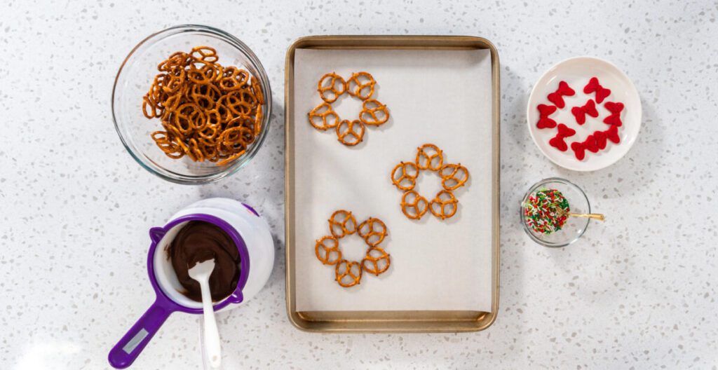 pretzels arranged like wreaths on a cookie sheet with ingredients in bowls on the side