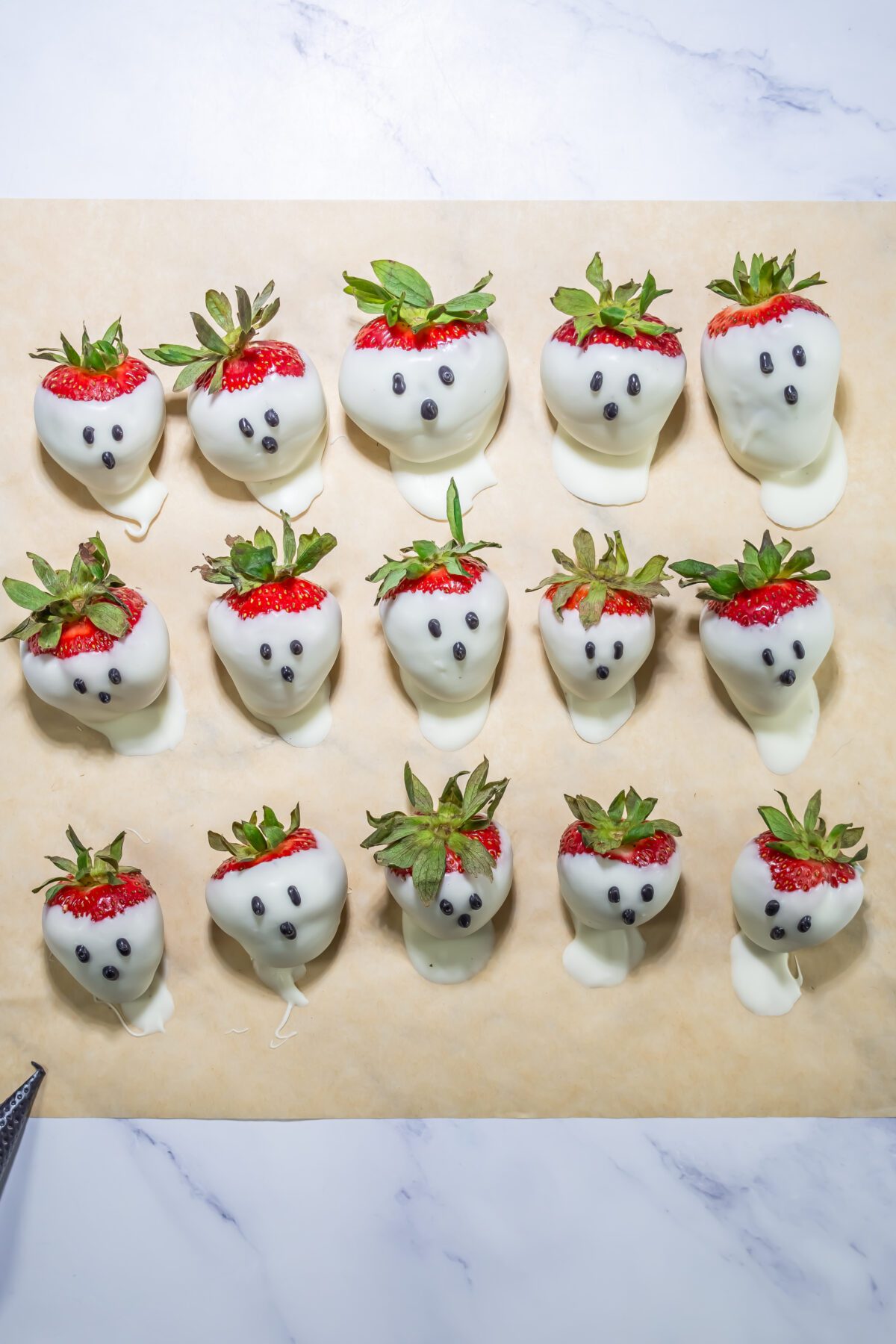 white chocolate covered strawberry ghosts on a parchment