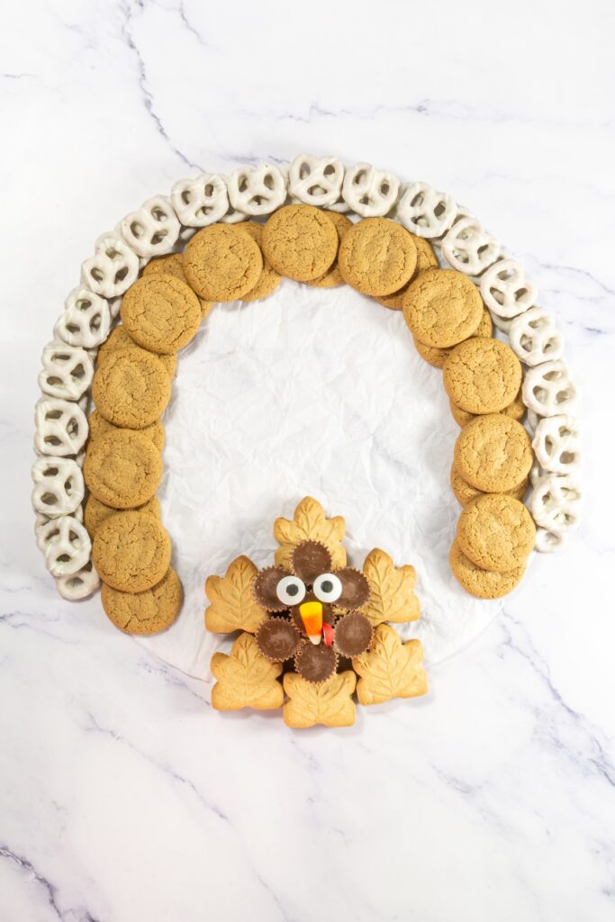 process photo of putting together a thanksgiving dessert charcuterie board that will look like a turkey when complete