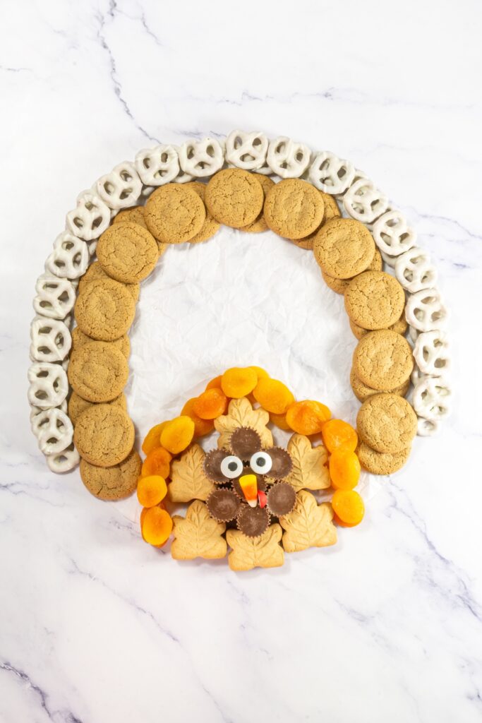 process photo of putting together a thanksgiving dessert charcuterie board that will look like a turkey when complete