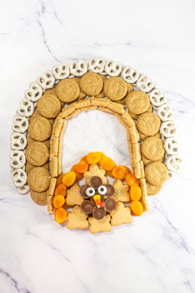 process photo of putting together a thanksgiving dessert charcuterie board that will look like a turkey when complete