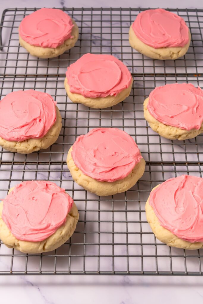 pink frosted sugar cookies on a cooling rack